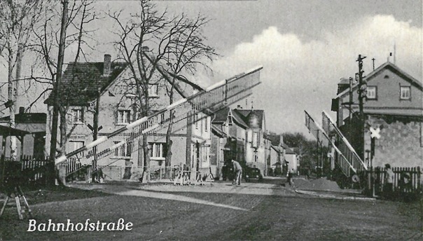 Der Bahnübergang auf einer Postkarte von 1958. Zu sehen ist die Bahnhofstraße in Fahrtrichtung Hausen.