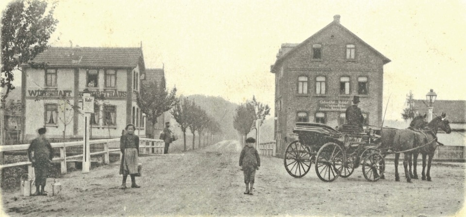 Noch nahezu unverbaut präsentierte sich um 1900 der Blick von Obertshausen über den Bahnübergang in Richtung Hausen. Links ist die Wirtschaft „Zum Forsthaus“, rechts die Gaststätte „Zum Bahnhof“ zu sehen.